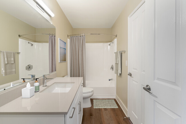 Renovated Package I bath with beige granite countertops, white cabinetry, and hard surface flooring - eaves Lake Forest