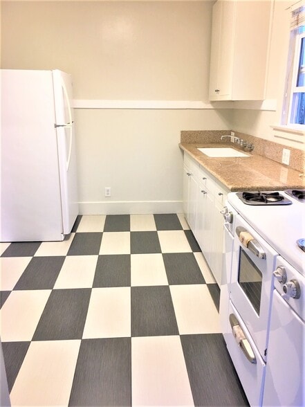 Kitchen granite countertop and tiled floor, refrigerator and stove - 3047 E 6th St