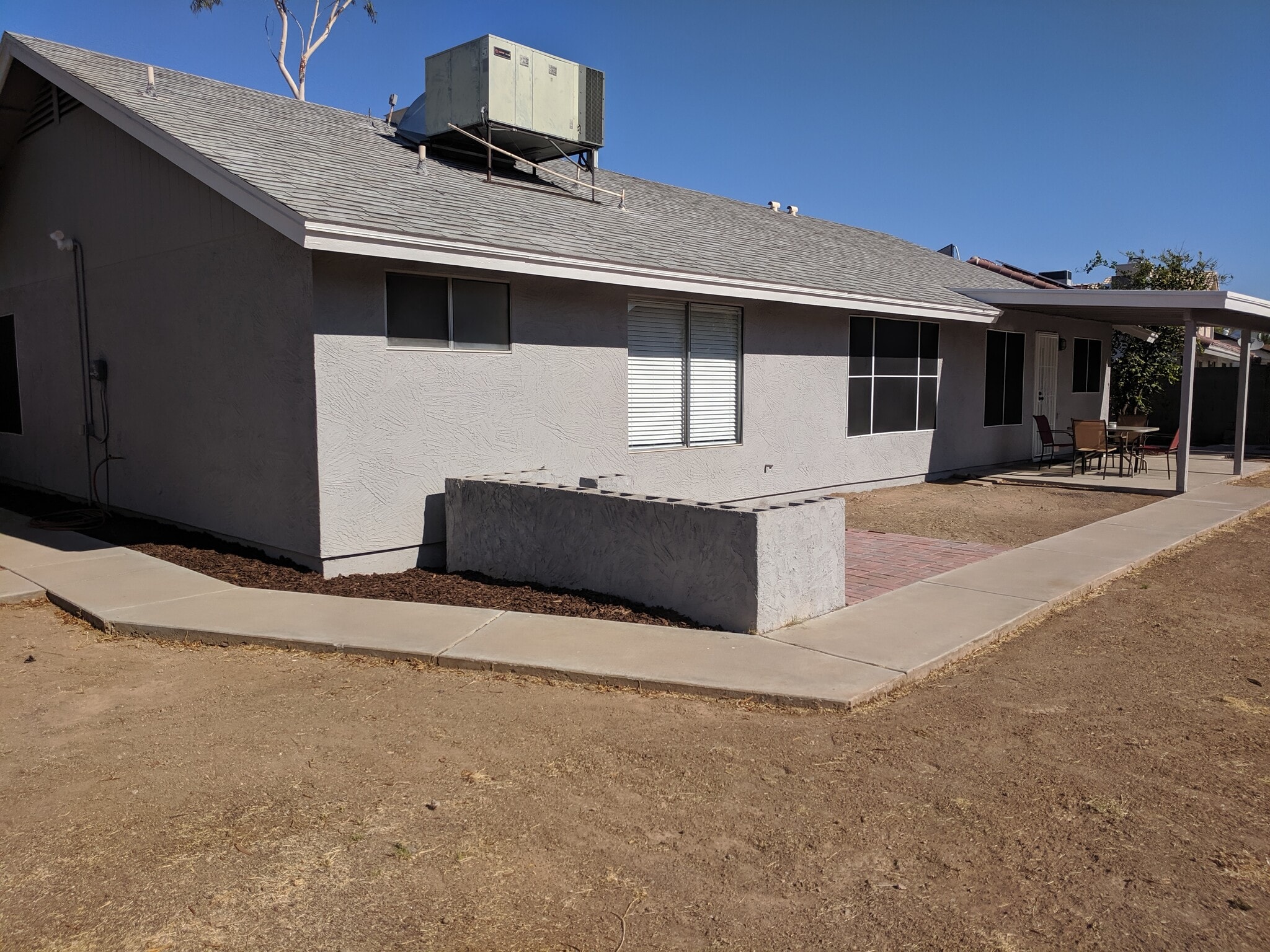 Back of home, facing west. AC unit recently serviced and in great condition. Master bdrm window and bath window in picture. - 14101 N 78th Dr