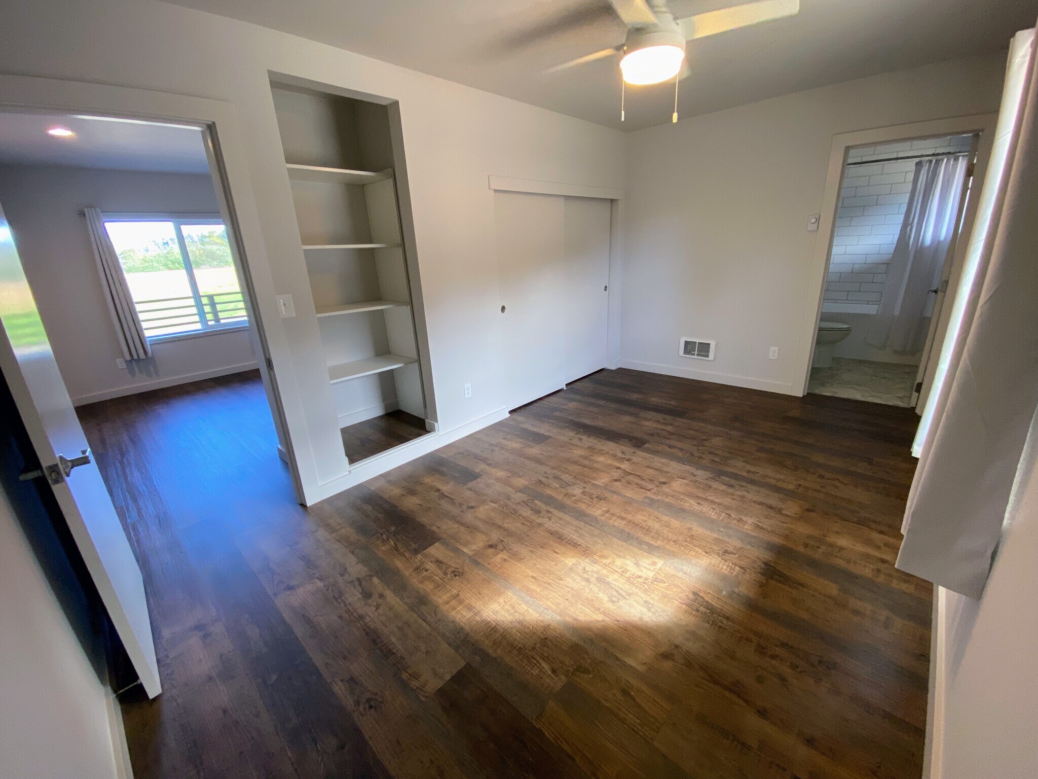 Bright, spacious bedroom with large window and elegant dark wood-style flooring. - 575 Greenwood Ave