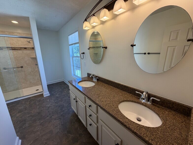 Spacious Primary Bath features double sinks, granite top, updated lighting and mirrors - 6419 Woodmont Rd