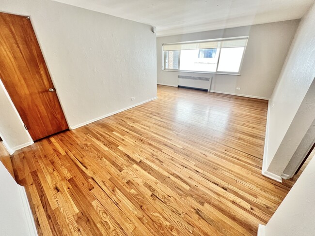 Experience the warmth and elegance of this open living area with stunning hardwood floors. - The Birney Apartments