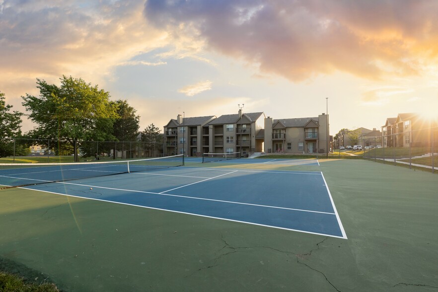 Ace your game at The Lakes community tennis courts, with stunning views of the apartment buildings in the background! - The Lakes Apartments