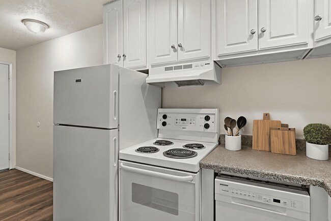 Bright and functional kitchen, staged with clean white appliances, ample cabinet space, and modern countertop accents. - Highland Court Apartments
