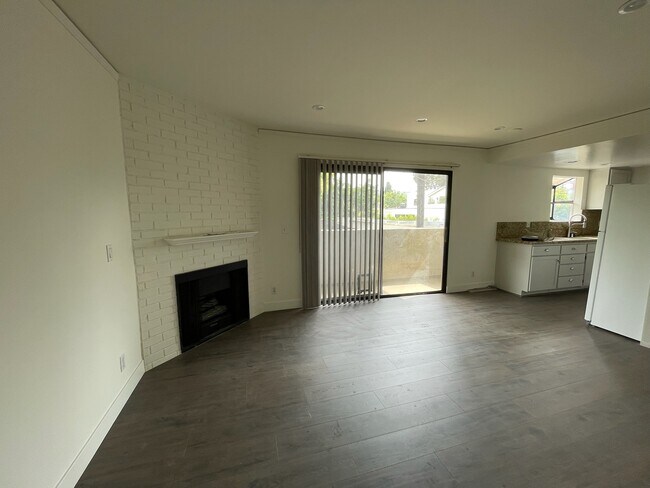 Living room with gas fireplace & sliding door to balcony next to kitchen - 10330 Riverside Dr