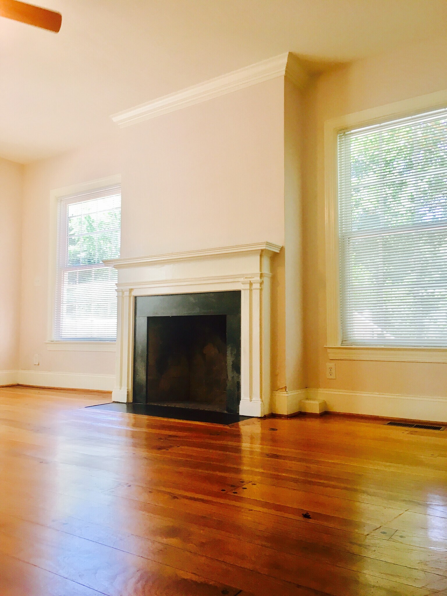 Living area with high ceilings, hardwood floors, and bright windows facing greenery. - 1937 Fairfield Dr