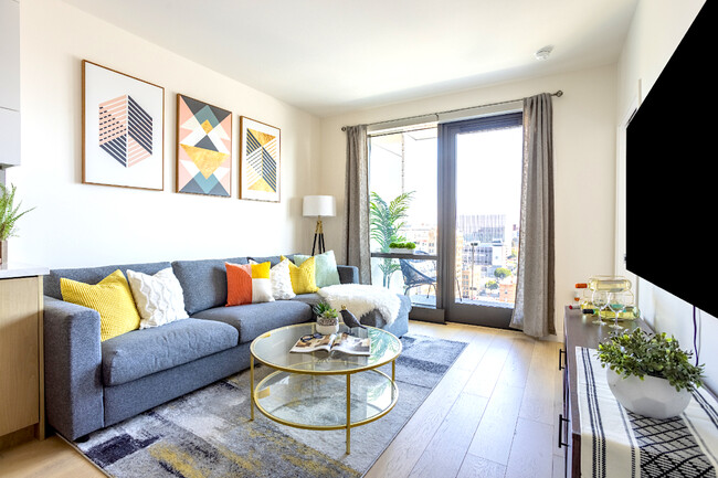 This cozy living room boasts a sectional sofa and large windows that let in plenty of natural light - 400 S Broadway