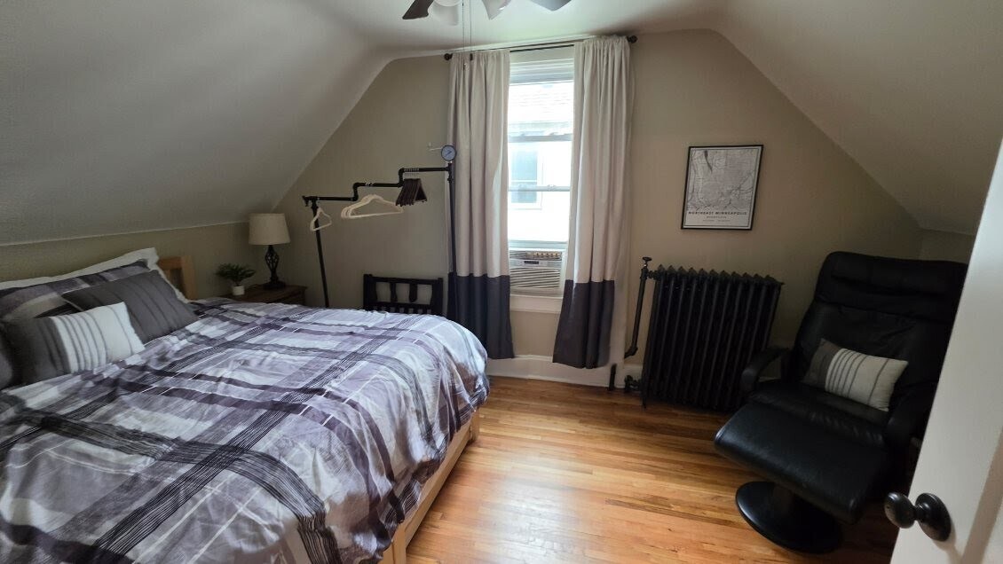 King bedroom with massage chair, clothing rack, and seasonal window AC. - 1901 -2301 Fillmore Street NE Minneapolis, MN 55418