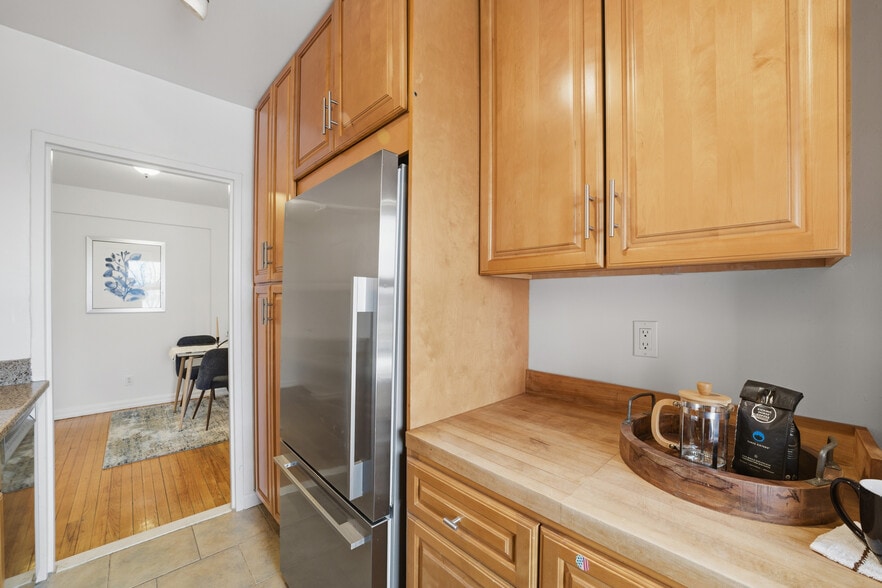 Kitchen featuring stainless steel appliances, wood cabinetry and light stone countertops - 555 Broadway