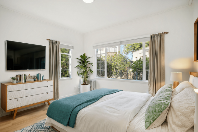 Bedroom with a large bed, comforter, a large window allows natural light to filter into the room - 2363 Le Conte Avenue