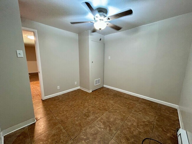 Inviting room with beige walls, modern ceiling fan, and chic tiled flooring, perfect for customization. - Boardwalk Apartments