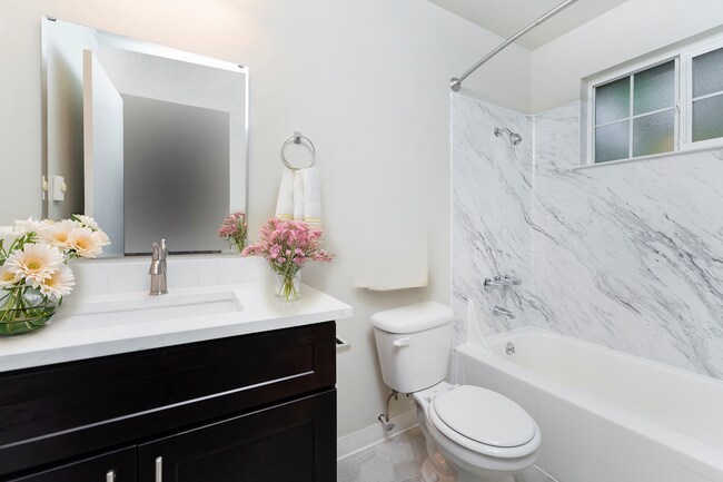 Experience luxury with this beautifully designed bathroom featuring marble accents and floral touches. - University Crossing Apartments