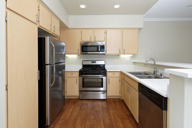 Kitchen with stainless steel appliances, laminate countertops, oak cabinetry, and hard surface flooring - Avalon Mission Oaks