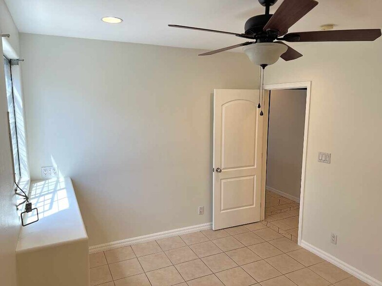 Second bedroom with large mirrored closet doors, ceiling fan, and window shelf. - 2330 S Mansfield Ave