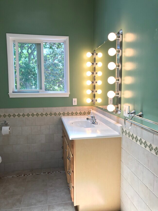 Master bath has custom tile, vaulted ceiling with skylight, and backyard view. - 14911 Fonthill Ave