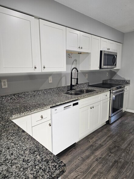 This clean kitchen layout offers granite stone finishes. - 8582 Chesapeake Blvd