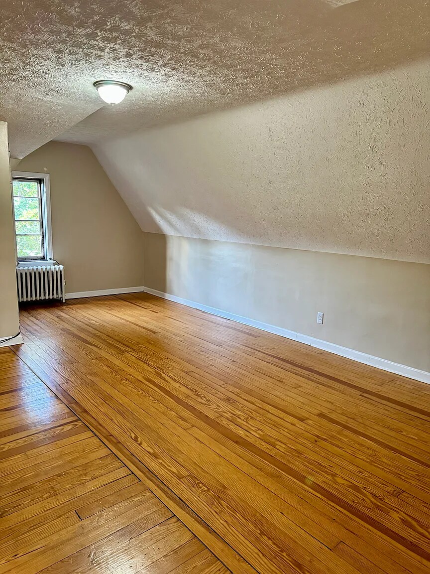 Third-floor bedroom with hardwood floors and cozy sloped-ceiling character. - 3682 Glencairn Road