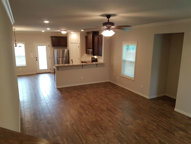 Living room and kitchen with granite counter-tops, fridge and microwave. Walk-in pantry. - 113 Ehlinger Dr