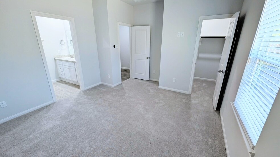 Primary bedroom is spacious and has an en suite bath, walk-in closet, and is pre-wired for a TV. - 13218 HP Johnson St