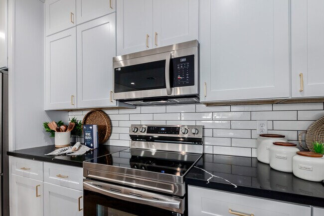 Kitchen with black & white marbled counters and white cabinets - The CJ Apartments