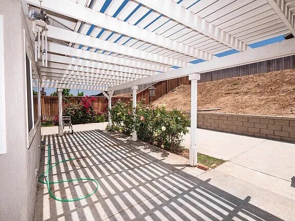 Covered patio with retaining wall and slope (maintained by gardener - included) - 4207 Rimcrest Dr