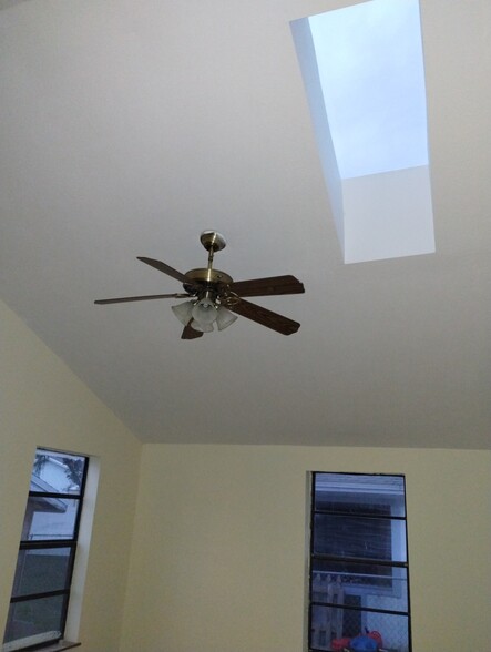 Master bedroom with cathedral ceiling, impact skylight, and paddle fan - 9018 SE Hobe Ridge Ave