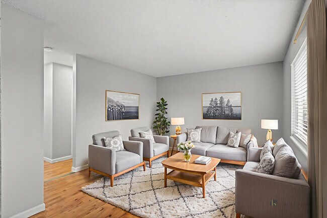 Inviting living room with modern decor, featuring plush gray seating, elegant artwork, and abundant natural light. - 5580 West 4th Avenue Townhomes