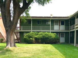 Cozy two-story apartment exterior with lush greenery and a welcoming courtyard. - GRACE LANDINGS APARTMENTS