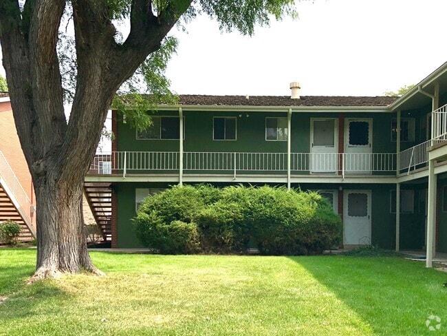 Cozy two-story apartment exterior with lush greenery and a welcoming courtyard. - GRACE LANDINGS APARTMENTS