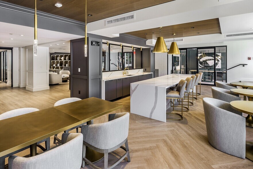 Elegant and modern communal area featuring luxurious seating, a sleek bar, cafe tables for working from home, and stylish pendant lighting at Parkside Place, apartments in Cambridge MA - Parkside Place