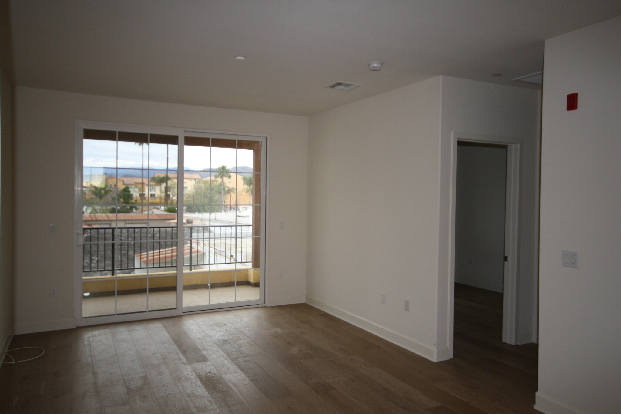 View of living room and balcony from kitchen area with door to guest room visible on right - 130 N Garden St