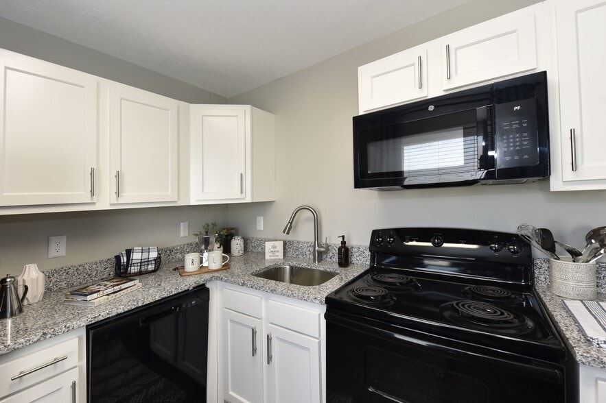 Kitchen with granite counters, modern cabinetry, and black appliance package - Reserve at Lindsay