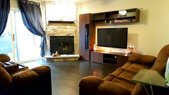 Living room with floating flat screen TV and fireplace with stone facade - 1920 Tracy Drive