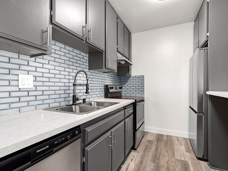 White tiled kitchen with stainless steel fridge, microwave, and oven. - Chandler Circle