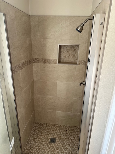 Shower in primary suite offers beautifully crafted tile. - 128 Dallas St