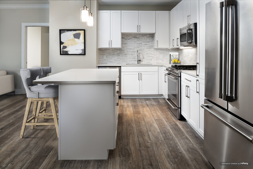 Signature Collection kitchen with white cabinetry, light grey quartz countertops, white marbled subway tile backsplash, stainless steel appliances, and hard surface flooring - Avalon Rockville Centre