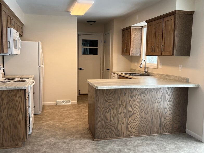 Kitchen offers a pantry and features steps to lower level and door to garage - 835 Maple St NE