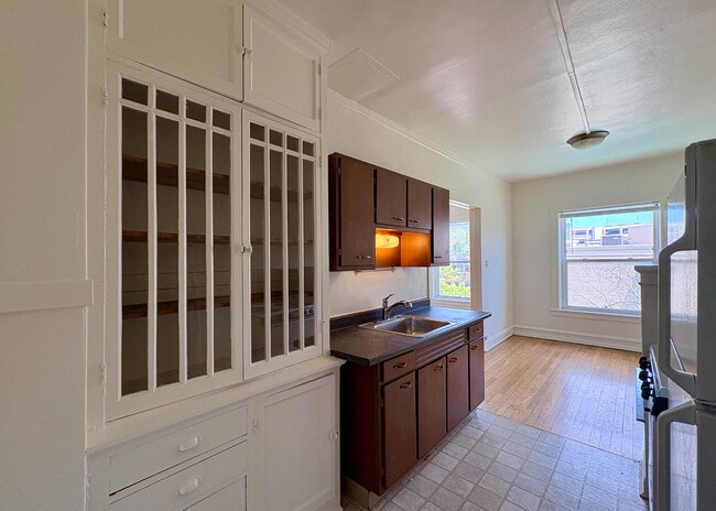 Bright and inviting kitchen with sleek wooden cabinets, a large window for natural light, and classic built-in shelving, offering a perfect blend of style and functionality. - Ivanhoe