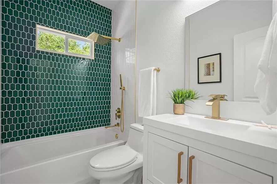 High end gold finishes elevate the captivating emerald green tiling in this spacious shared bathroom - 5402 Duval St