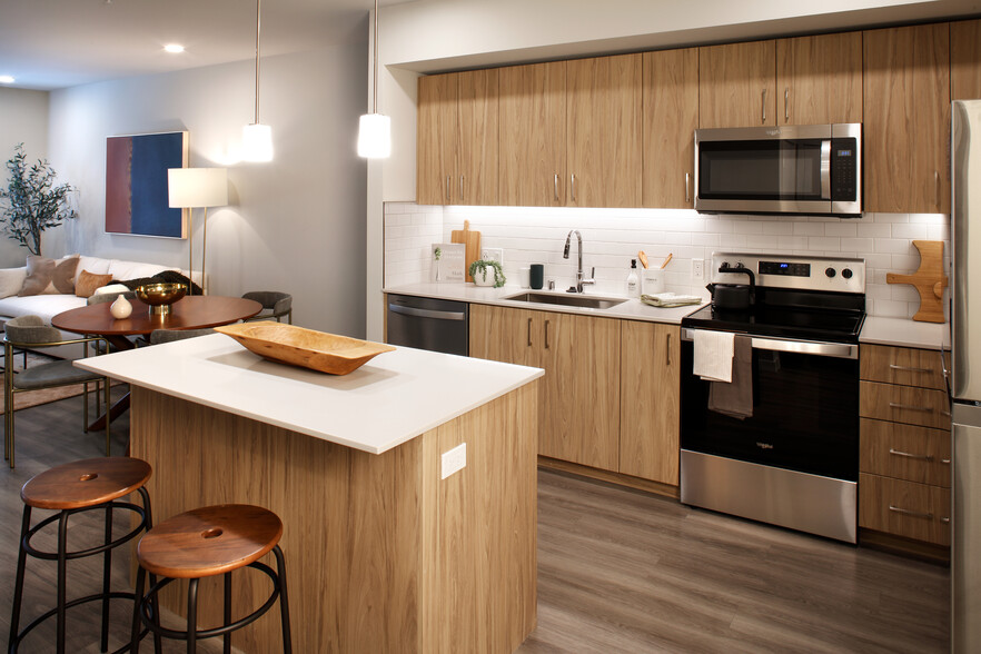 Design Collection II Kitchen with oak cabinetry, white quartz countertops, and white tile backsplash - Avalon Alderwood Place