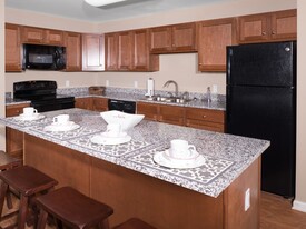 Enhance your student living with cherry wood cabinets, granite countertops, and sleek black appliances at University Hills Apartments - University Hills