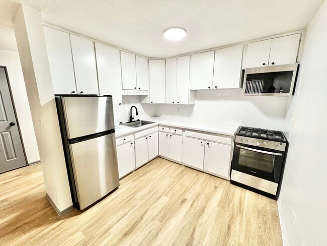 Explore this sleek kitchen design with contemporary finishes and ample cabinet space. - Melody Apartments