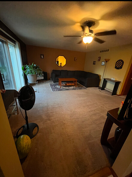 Large living room with sliding glass doors leading to a secluded deck and 2 acre backyard - 4300 E 73rd Ave