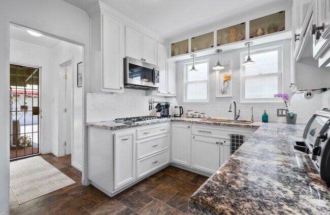 Gas stovetop with hallway to the back patio and second bathroom. - 1150 W 25th St