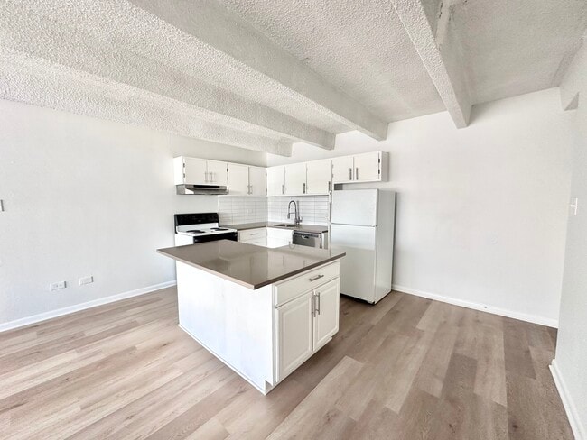 Modern kitchen with sleek countertops, stylish cabinetry, and spacious layout featuring an elegant island centerpiece. - Columbine Plaza