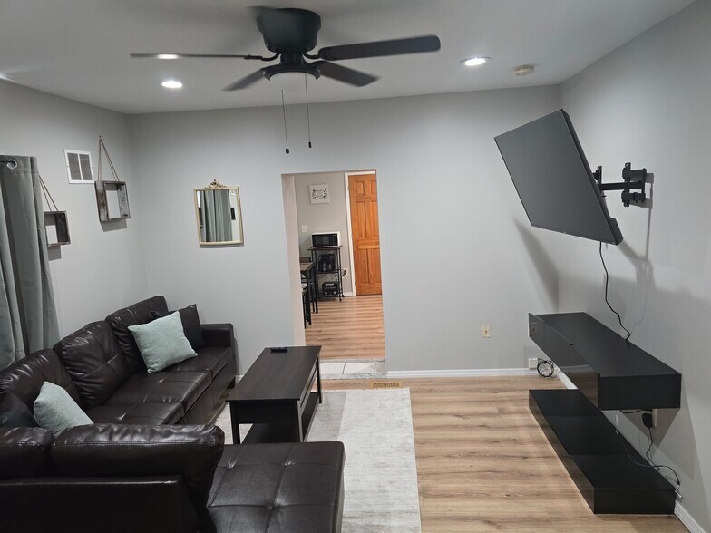 View of living room from the side and doorway into kitchen. Large smart TV mounted on the wall. - 510 North St