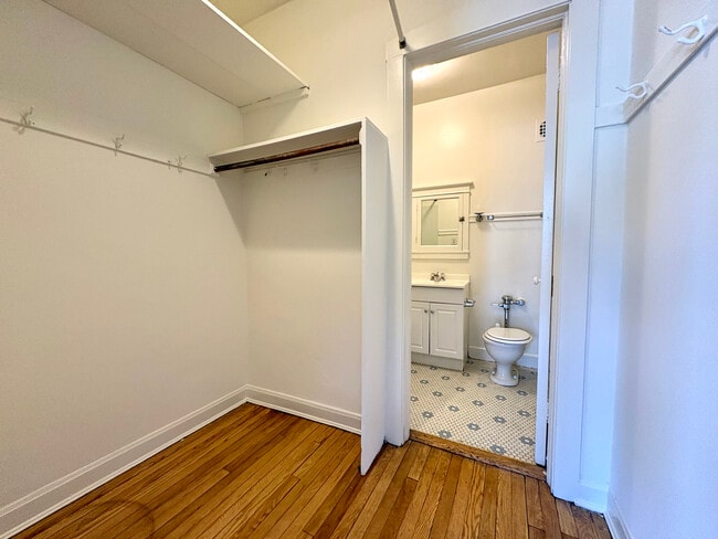 Inviting walk-in closet with hardwood floors leading to a modern bathroom with stylish fixtures. - Ivanhoe