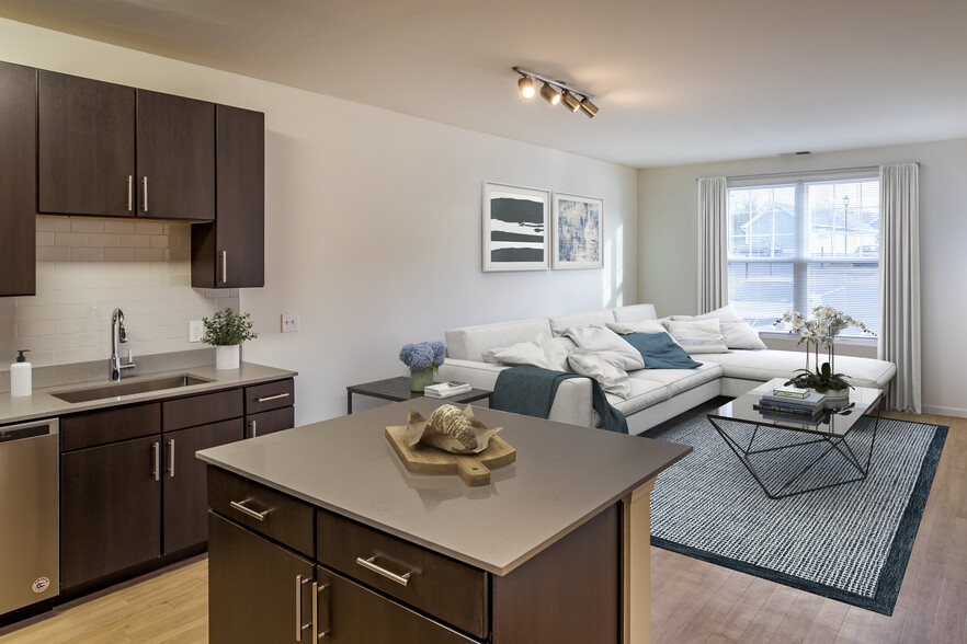 Newly renovated apartment homes feature kitchens with espresso cabinetry, grey quartz countertops, stainless steel appliances, grey tile backsplash, and hard surface flooring - Avalon Huntington Station