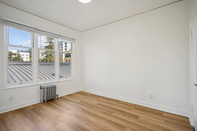 Spacious bedroom with a large window offering a view of a cityscape - 2605 Haste Street