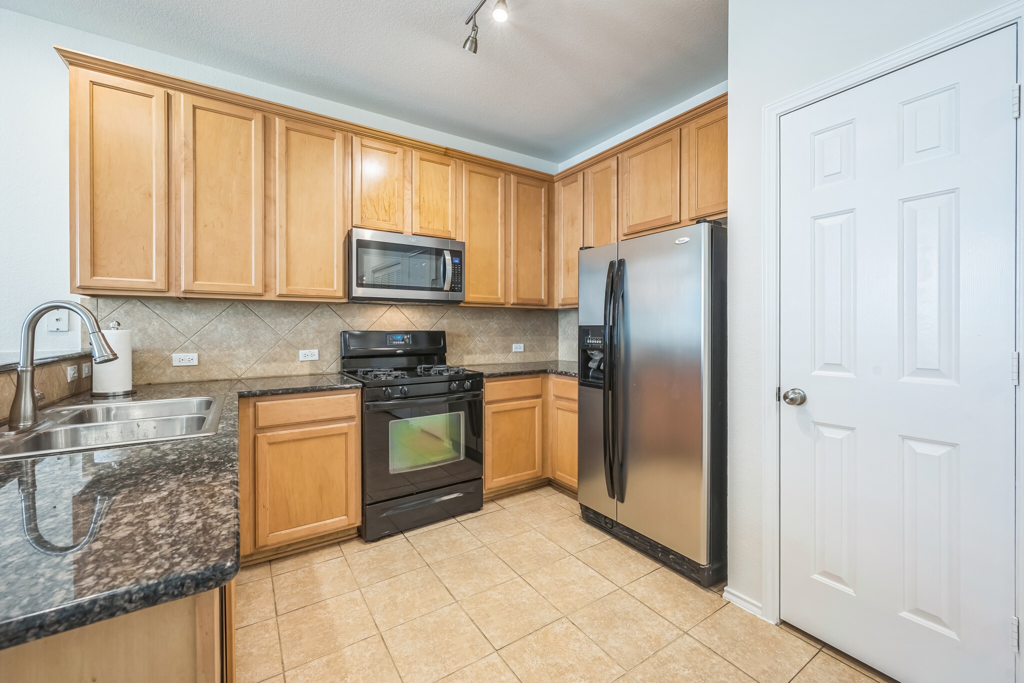 Kitchen with granite counters, appliances and door to pantry - 9201 Brodie Ln